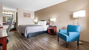 Una habitación de hotel con cama, mesitas de noche, escritorio, silla y lámpara.