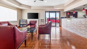A spacious living area with a fireplace, leather sofas, and a tiled floor.