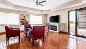 A spacious living room with a fireplace, a ceiling fan, and a large window.