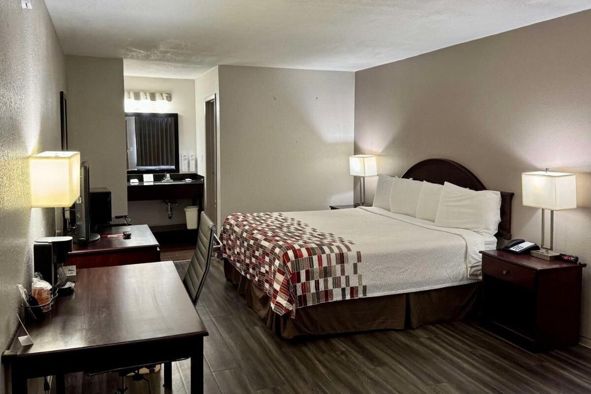 A hotel room with a bed, bedside tables, a desk, and a chair.