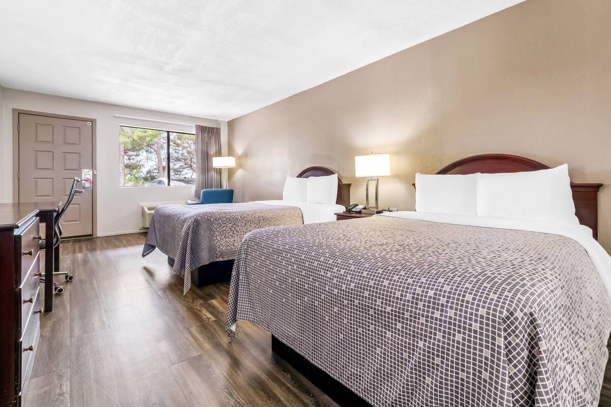 A hotel room with two beds, a desk, and a chair.