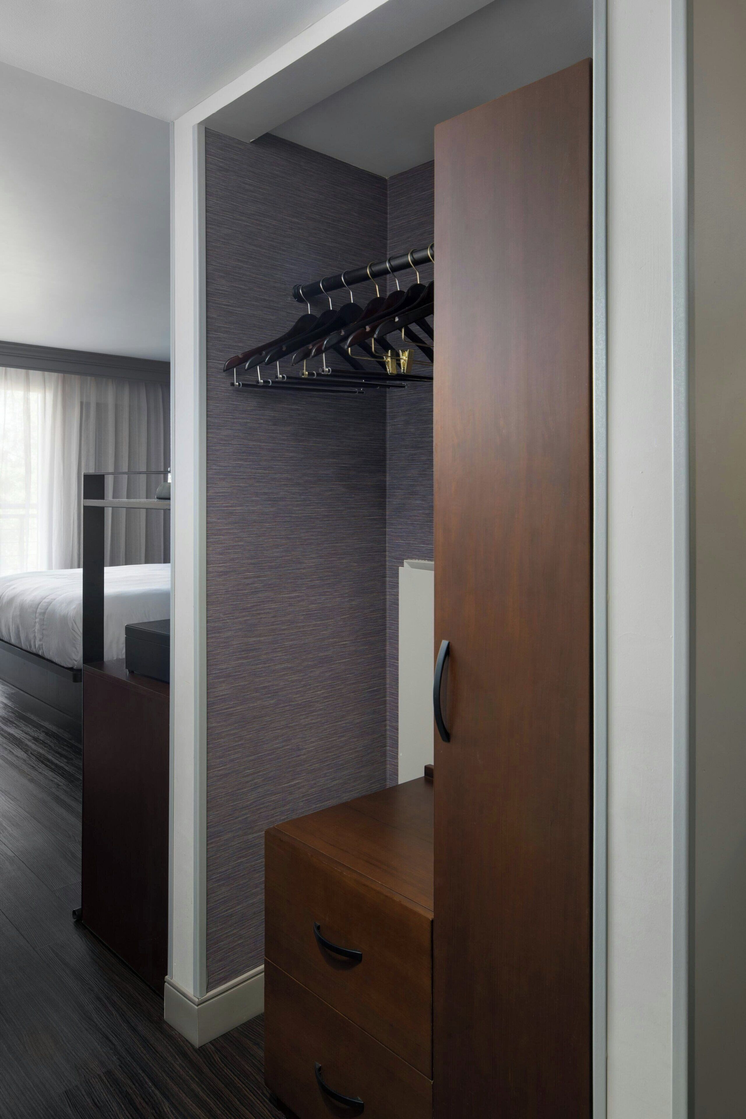 Una habitación de hotel con una cama litera, un aparador de madera y un perchero.