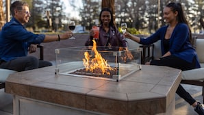 A fire pit table with a clear glass enclosure, surrounded by outdoor seating. - Visalia Marriott at the Convention Center (Visalia)