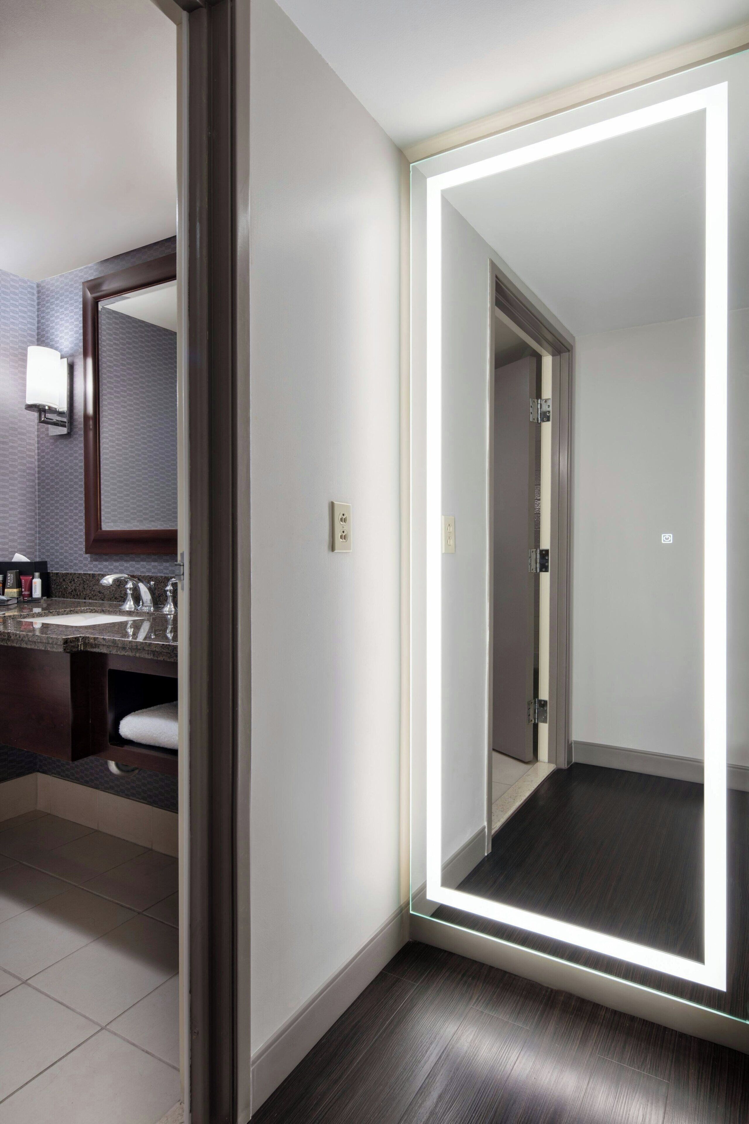 A modern hotel bathroom with a large mirror, a sink, and a toilet.