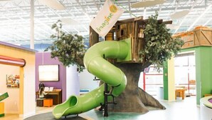 An indoor play area with a green slide, a wooden play structure, and a banner that reads "Imagine." - Visalia Marriott at the Convention Center (Visalia)