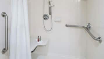 A walk-in shower with a grab bar, a showerhead, and a white tiled wall.