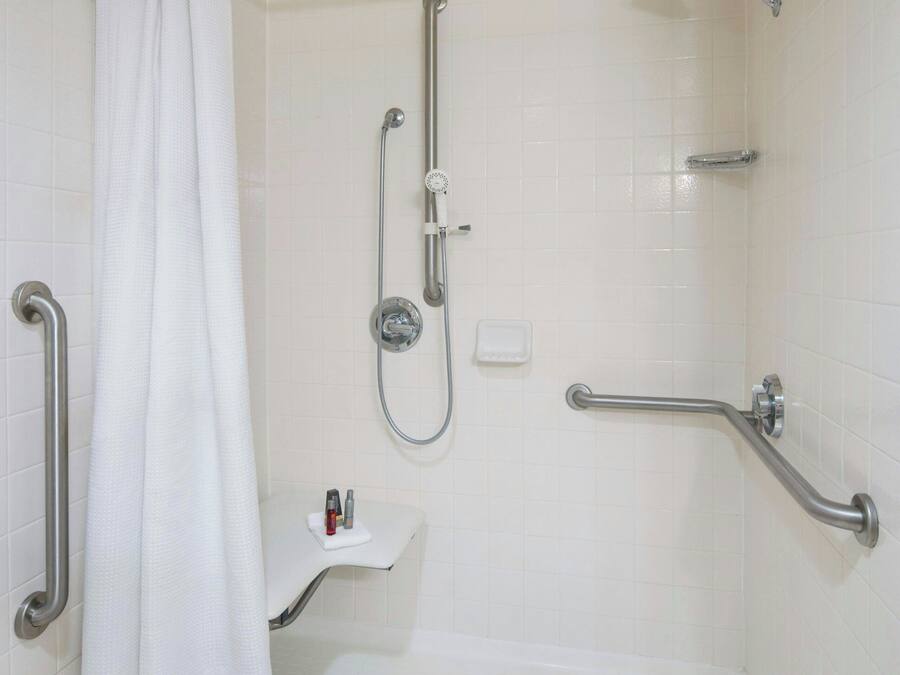 A walk-in shower with a grab bar, a showerhead, and a white tiled wall.