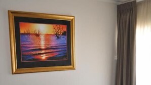 Ein Zimmer mit zwei schwarzen Ledersesseln, einem gerahmten Gemälde einer Untergangsszene und einem Fenster mit Vorhängen.