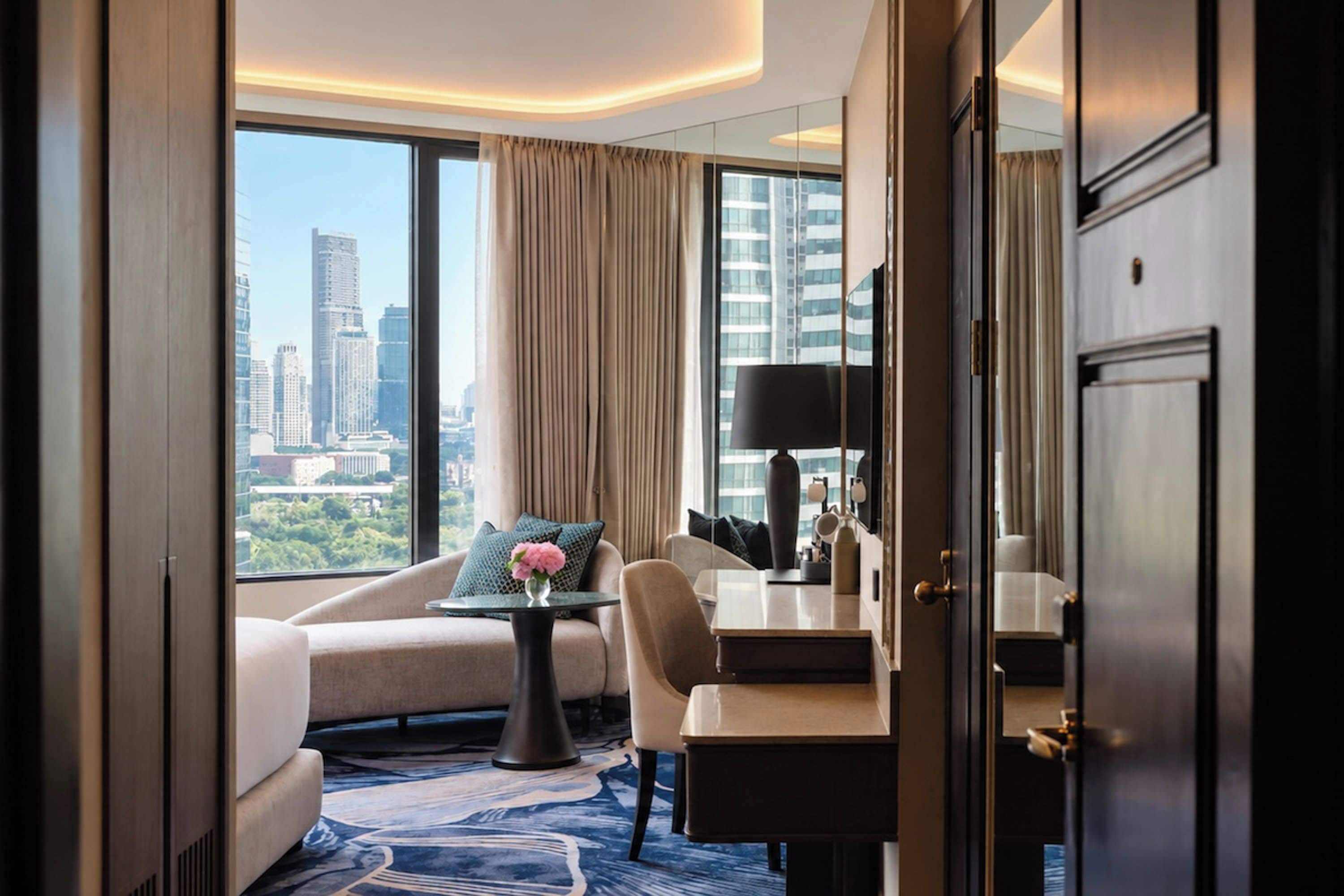 Habitación de hotel con vista a la ciudad, un sofá, una mesa de comedor y un espejo.