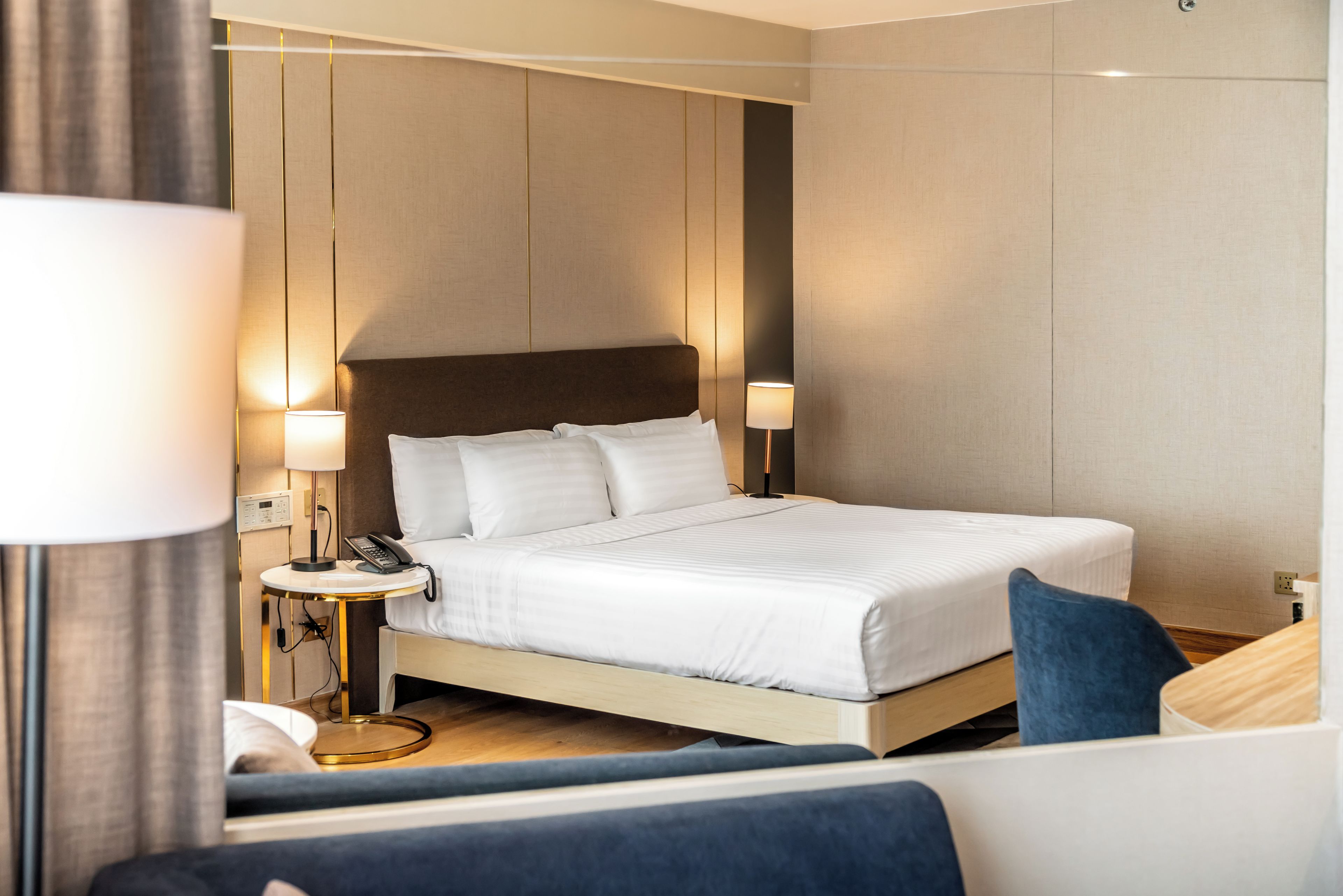 Una habitación de hotel moderna con una cama grande, mesitas de noche y un pequeño escritorio.