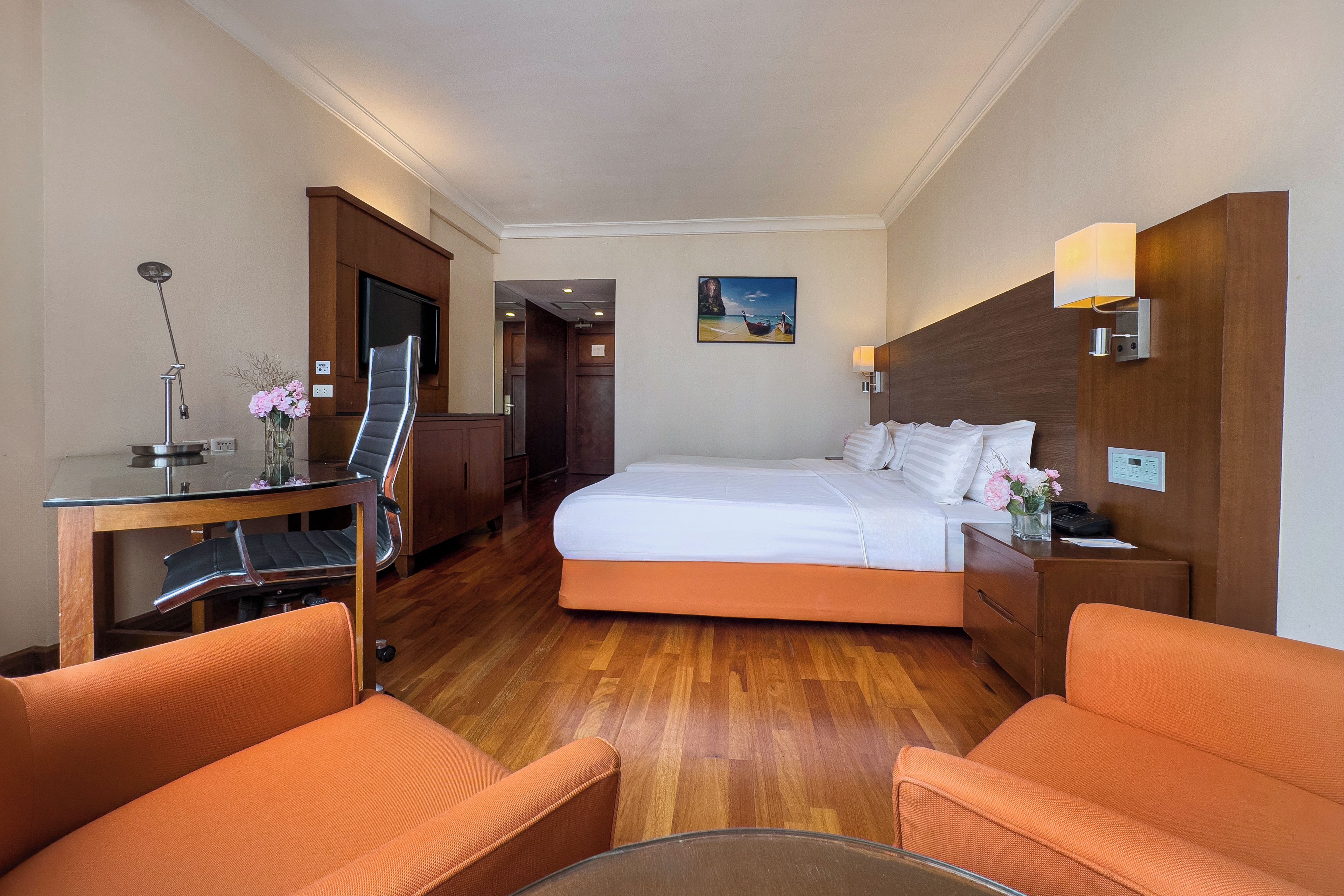 Une chambre d’hôtel avec un lit, un bureau et une chaise, une télévision et un tableau accroché au mur.