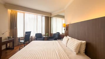 Una habitación de hotel con una cama grande, dos sillones, un escritorio y una lámpara.