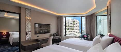 A hotel room with two beds, a desk, a TV, and a city view.