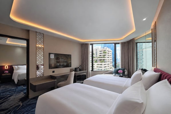 A hotel room with two beds, a desk, a TV, and a city view.