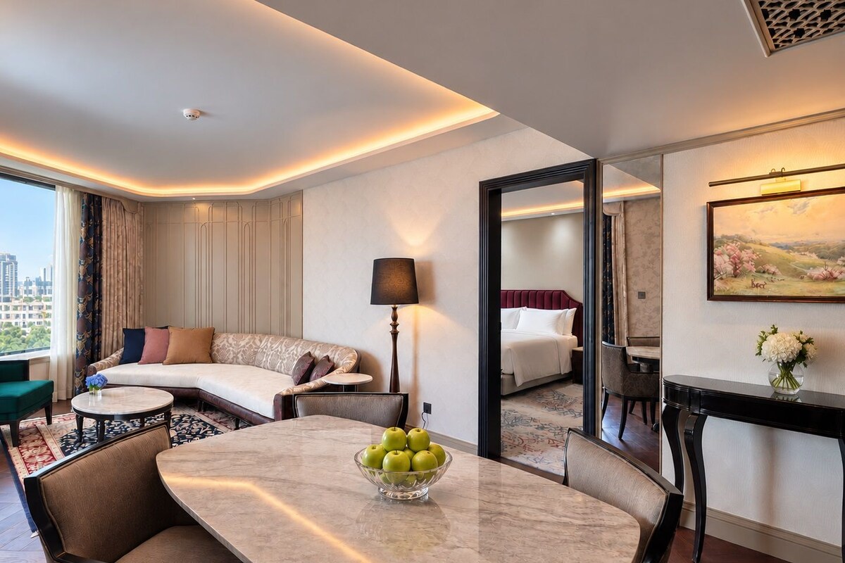 Een hotelkamer met een zithoek, een bank, een bed en een schilderij aan de muur.