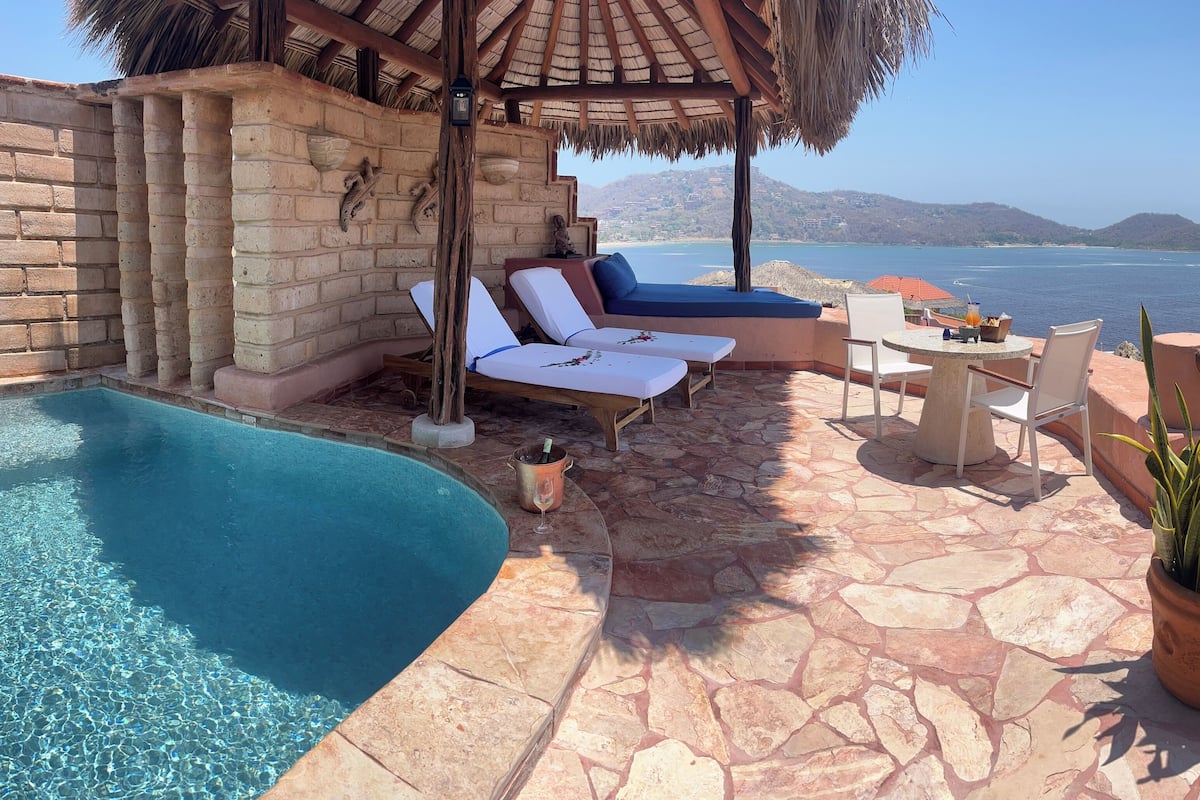 A poolside area with lounge chairs, a table, and a potted plant.