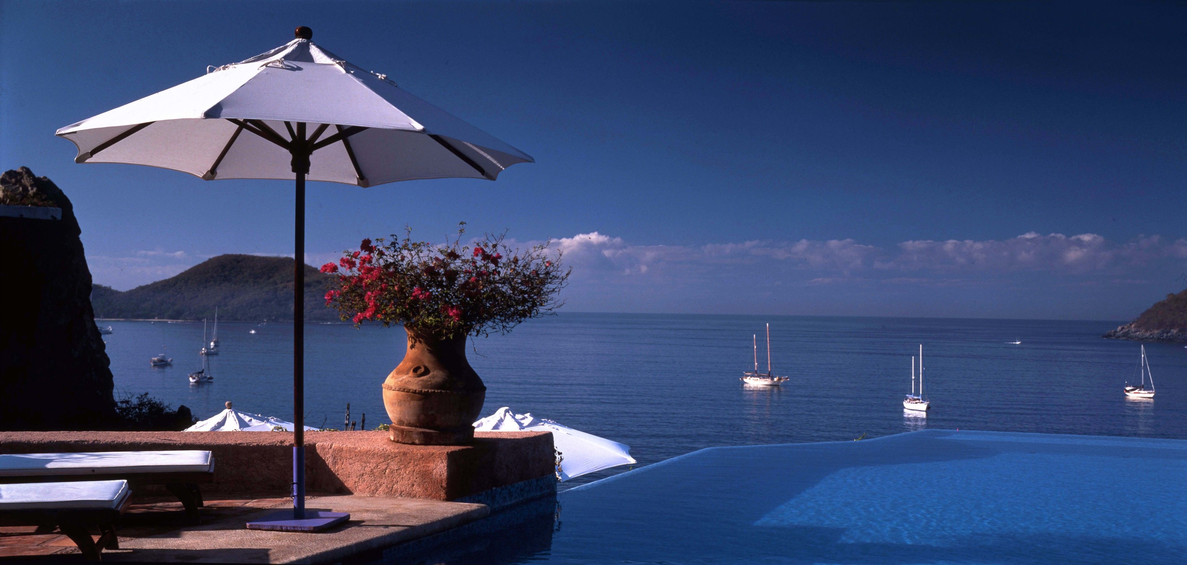 An infinity pool with a view of the sea and boats.