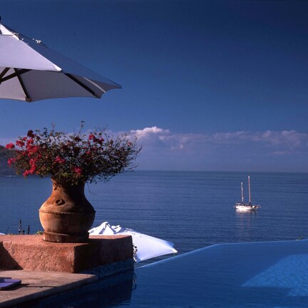 An infinity pool with a view of the sea and boats.