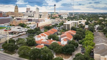 An aerial view of a cityscape with various buildings, a prominent tower, and a large parking area.