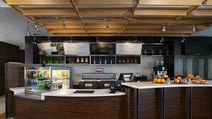 A modern bar area with a wooden counter, a refrigerated display, and a menu board.