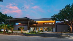 A Courtyard by Marriott hotel with a covered entrance, palm trees, and a landscaped area.