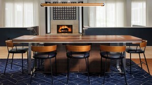 A modern dining area with a central island table, four chairs, and a fireplace.