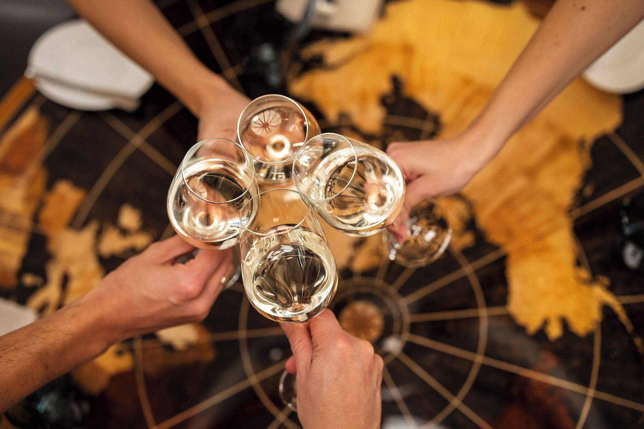 A group of people holding wine glasses in a circular arrangement.