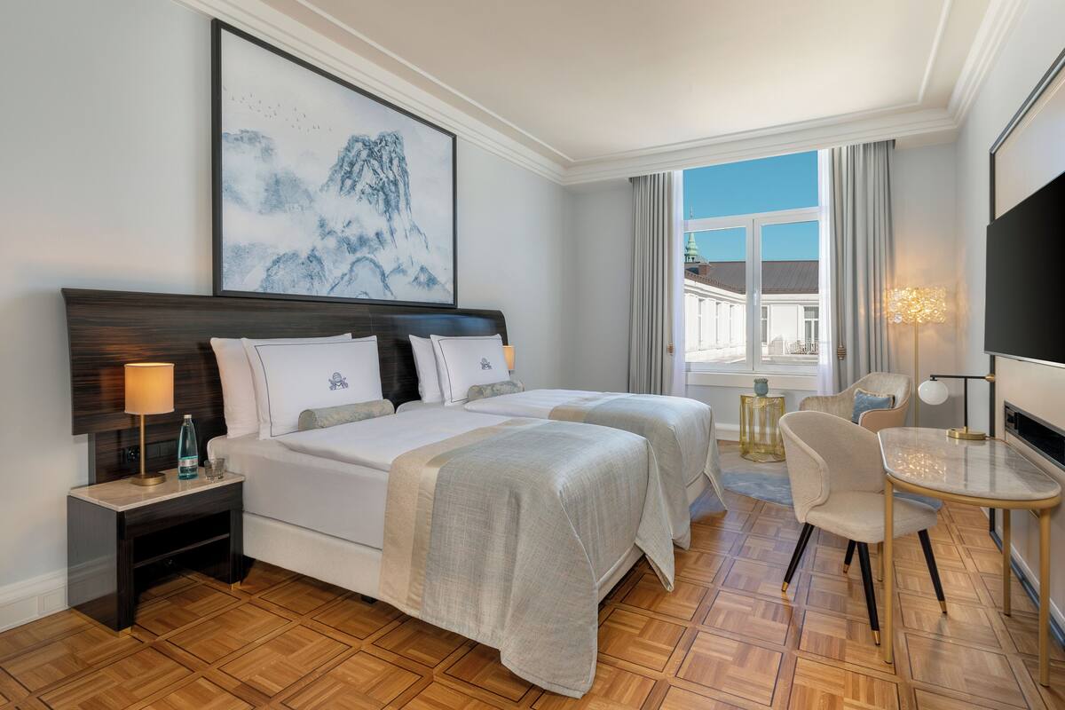 Habitación de hotel con una cama grande, un escritorio, una silla, un televisor y una ventana con vistas a edificios.
