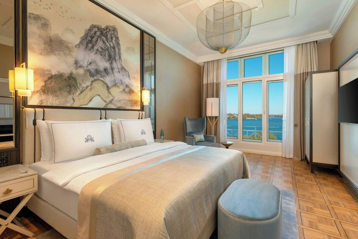 Habitación de hotel con una cama grande, un escritorio, una silla, un televisor y vista al mar.