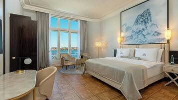 Habitación de hotel con una cama grande, un escritorio, una silla, vista al mar y un cuadro en la pared.