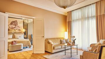 A hotel room with a bed, a sofa, a coffee table, and a large window with curtains.