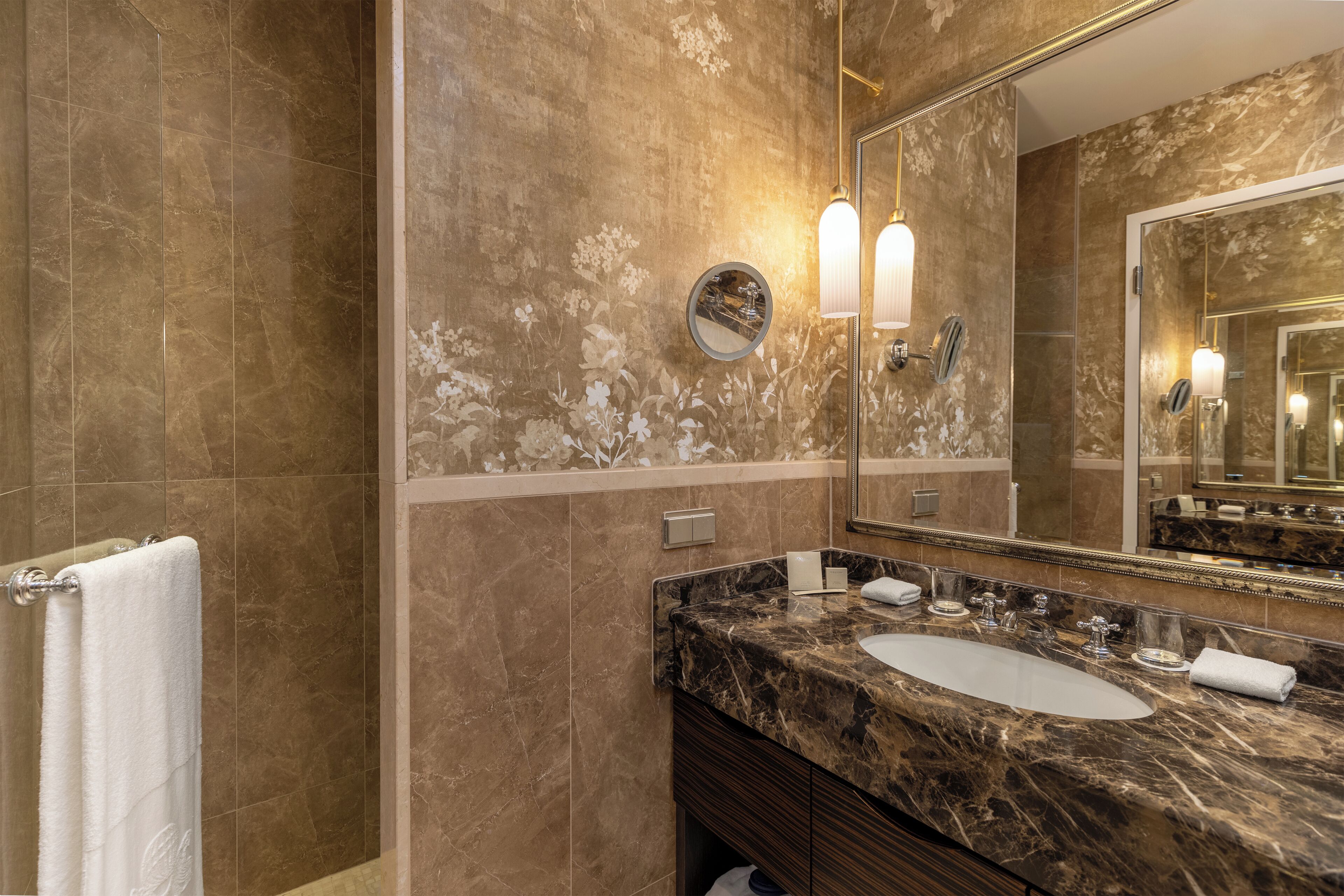 Une salle de bain avec un lavabo en marbre, un grand miroir et un porte-serviettes.