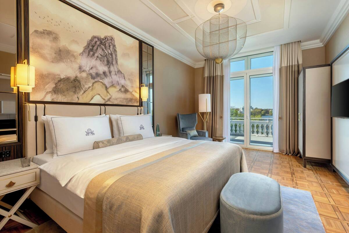 Habitación de hotel con una cama grande, un escritorio, una silla, un televisor y un balcón con vistas.