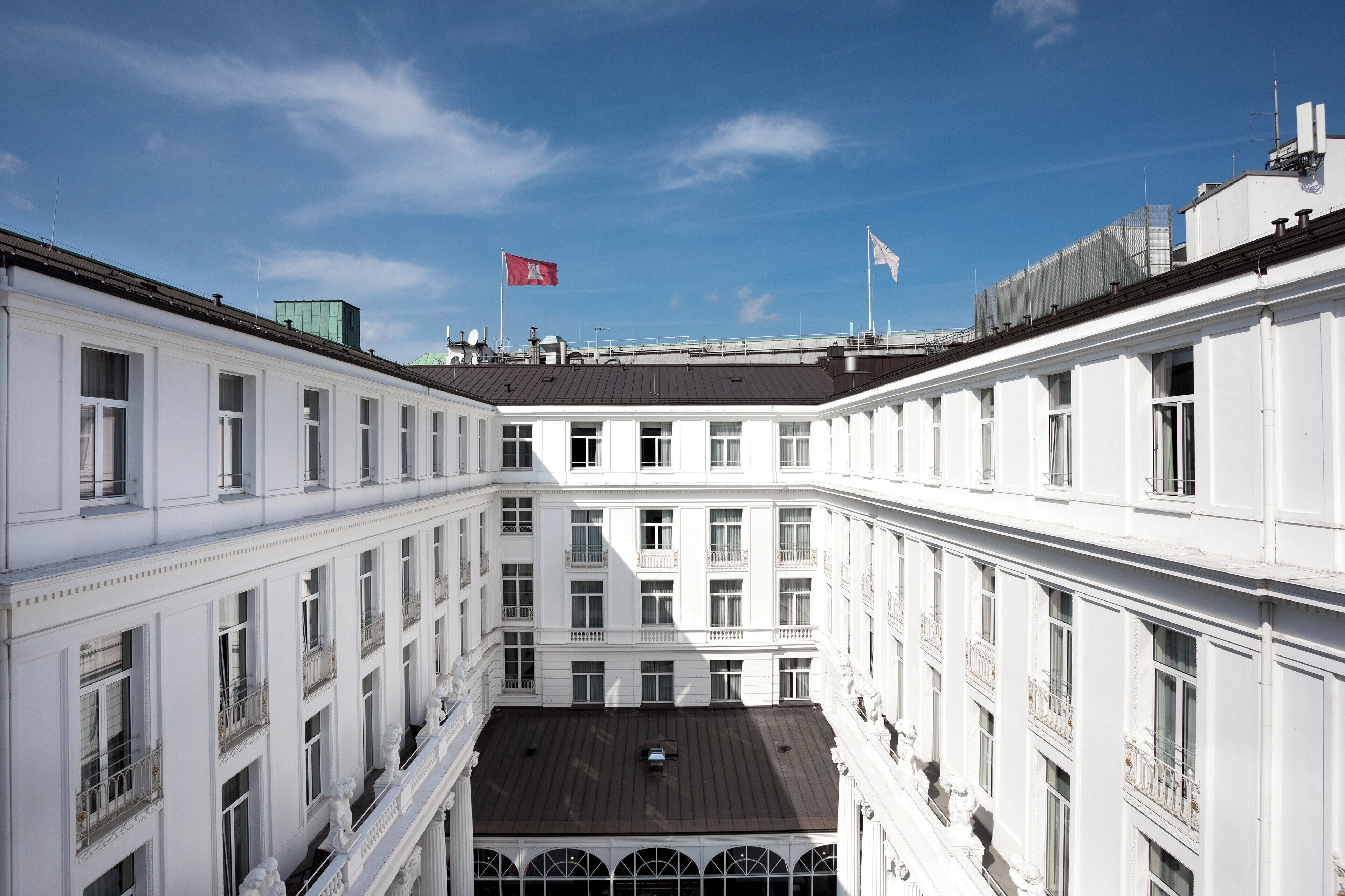 A multi-story building with a central courtyard, large windows, and a flag on top.