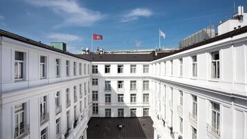 A multi-story building with a central courtyard, large windows, and a flag on top.