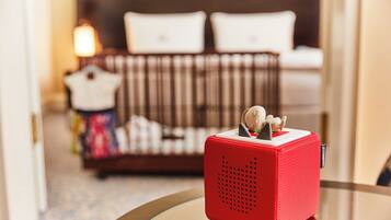 A red speaker on a glass table with a blurred background of a bed and a nightstand.