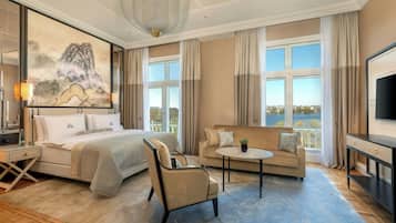 Habitación de hotel con cama, sofá, sillón, una mesita, televisión y un cuadro en la pared.