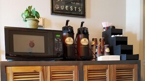 Une cuisine équipée d’un four à micro-ondes, de machines à café et d’une pancarte indiquant : « Réservé à nos clients ».