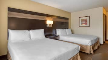 Una habitación de hotel con dos camas, un cabecero con una lámpara y un cuadro en la pared, además de una mesita.
