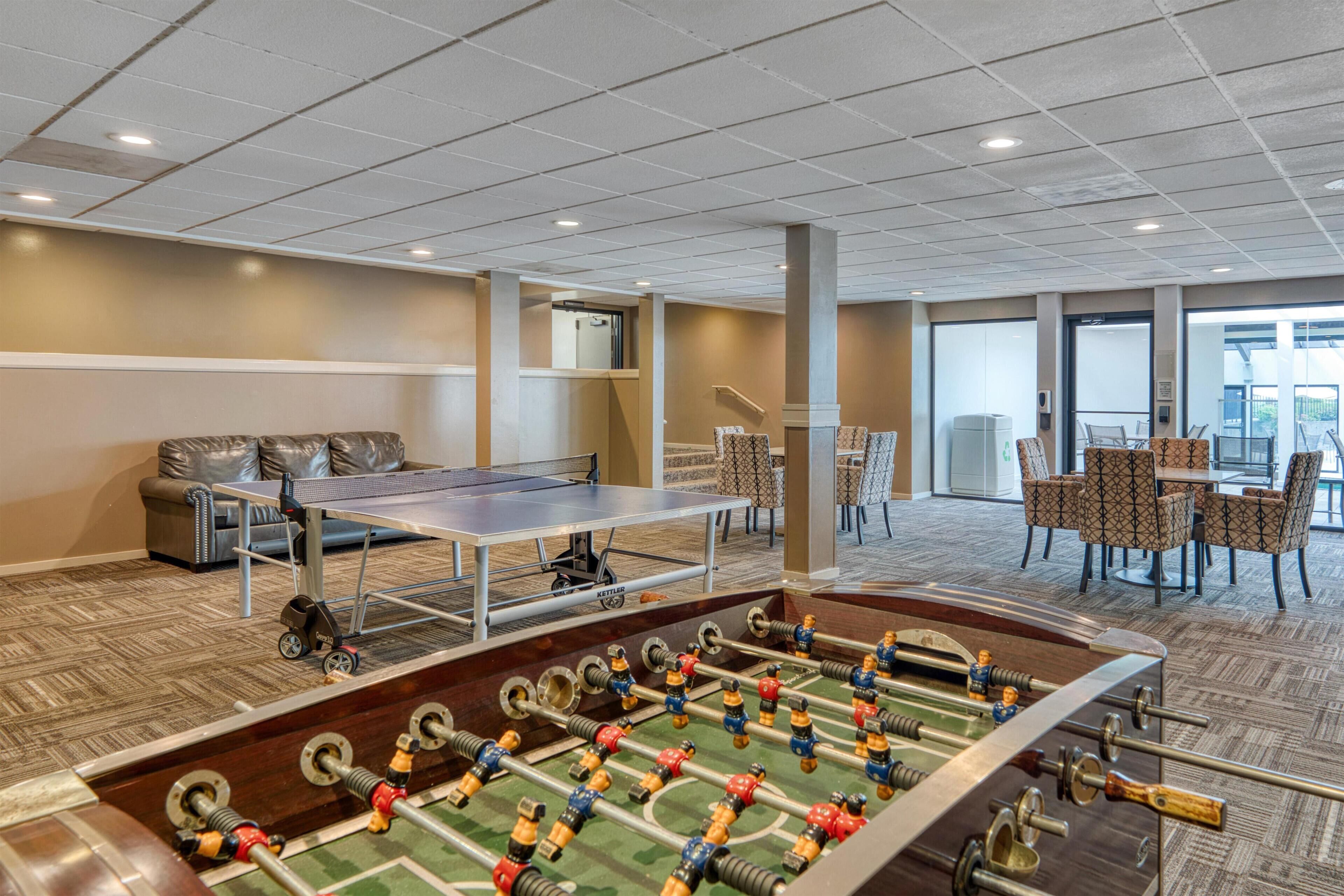 Una habitación con mesa de futbolín, mesa de ping pong y un sofá.