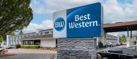 A Best Western hotel sign with a stone base and a blue and white color scheme.