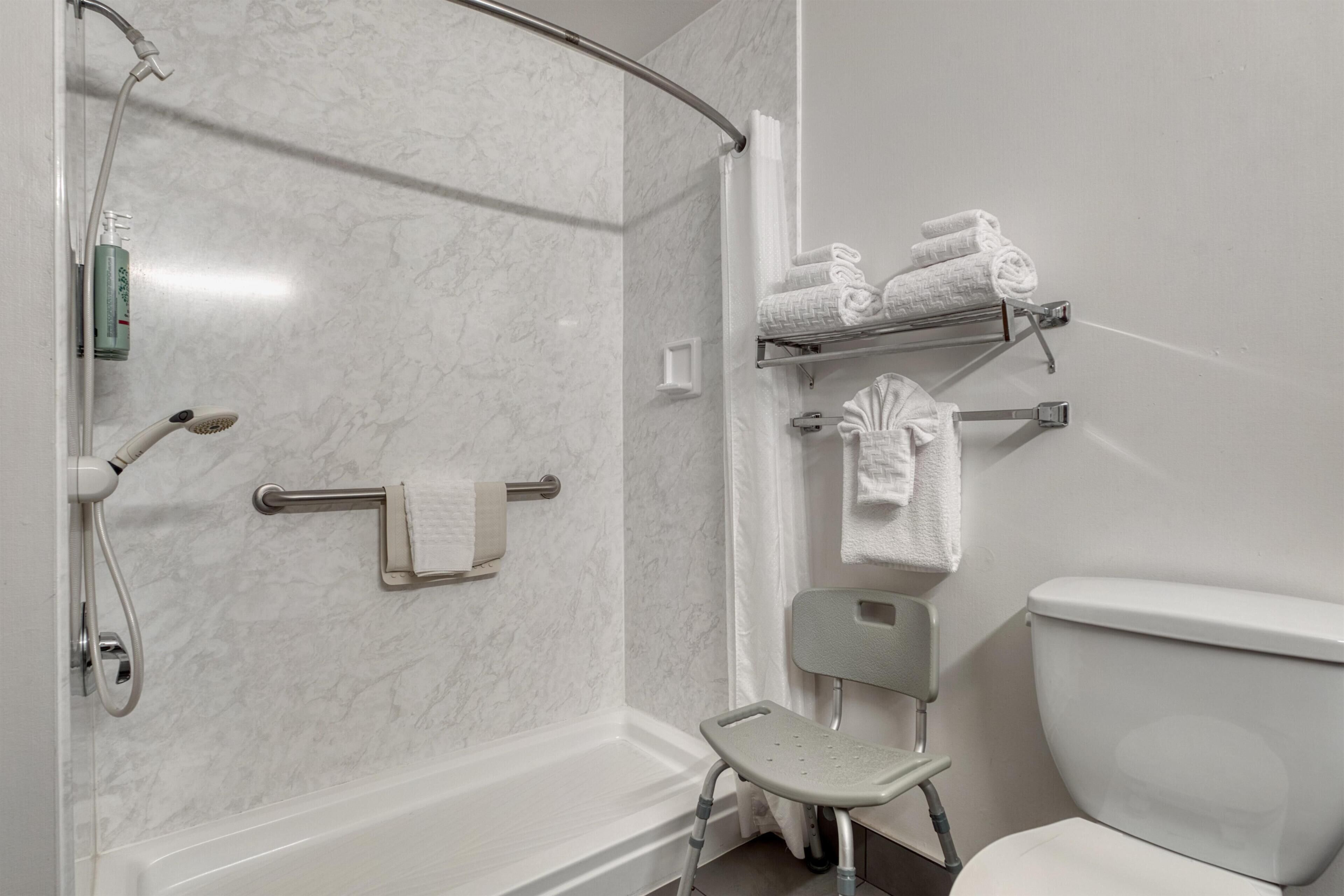Un baño con ducha, inodoro y una silla.