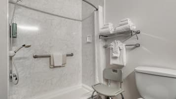 Un baño con ducha, inodoro y una silla.