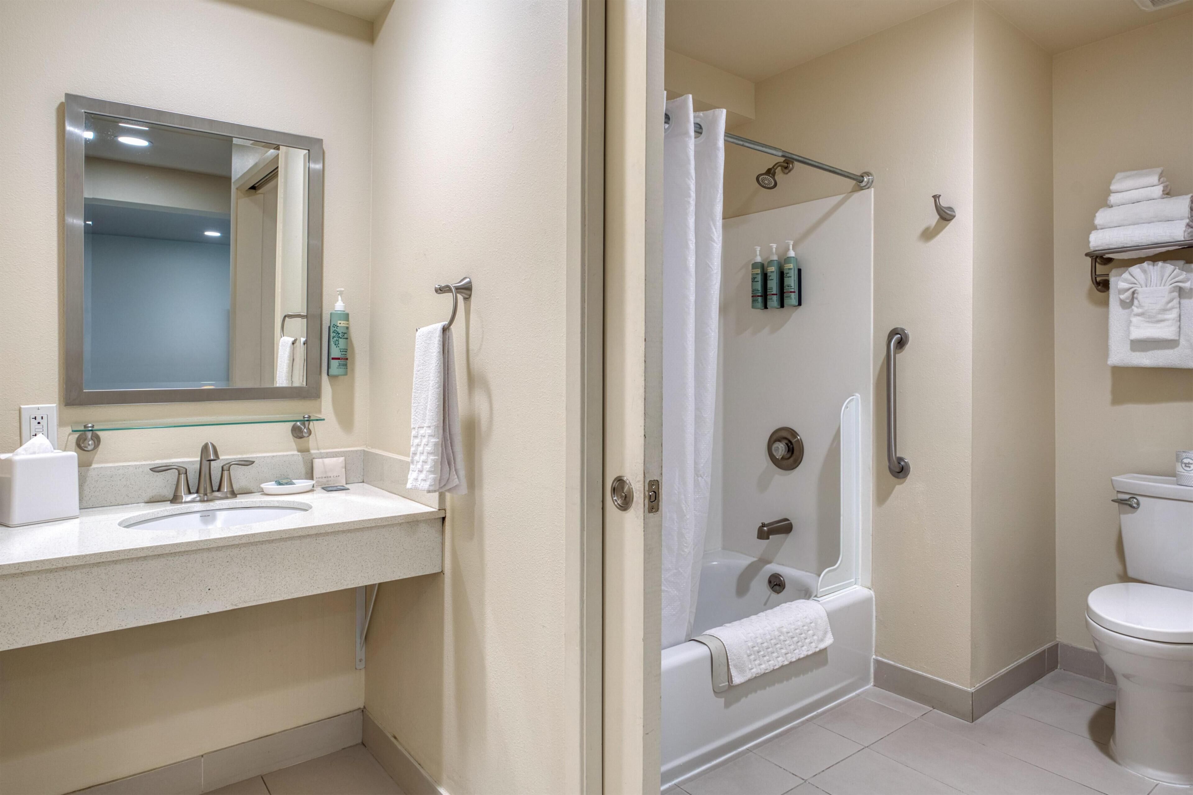 A bathroom with a sink, mirror, shower, and toilet.