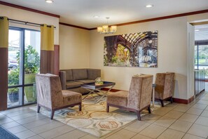 A lobby with a sofa, chairs, a coffee table, a painting, and a large window with curtains. - Best Western Seattle Airport Hotel (SeaTac)