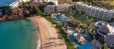 Un resort con varias edificaciones, una playa y una zona de piscina.
