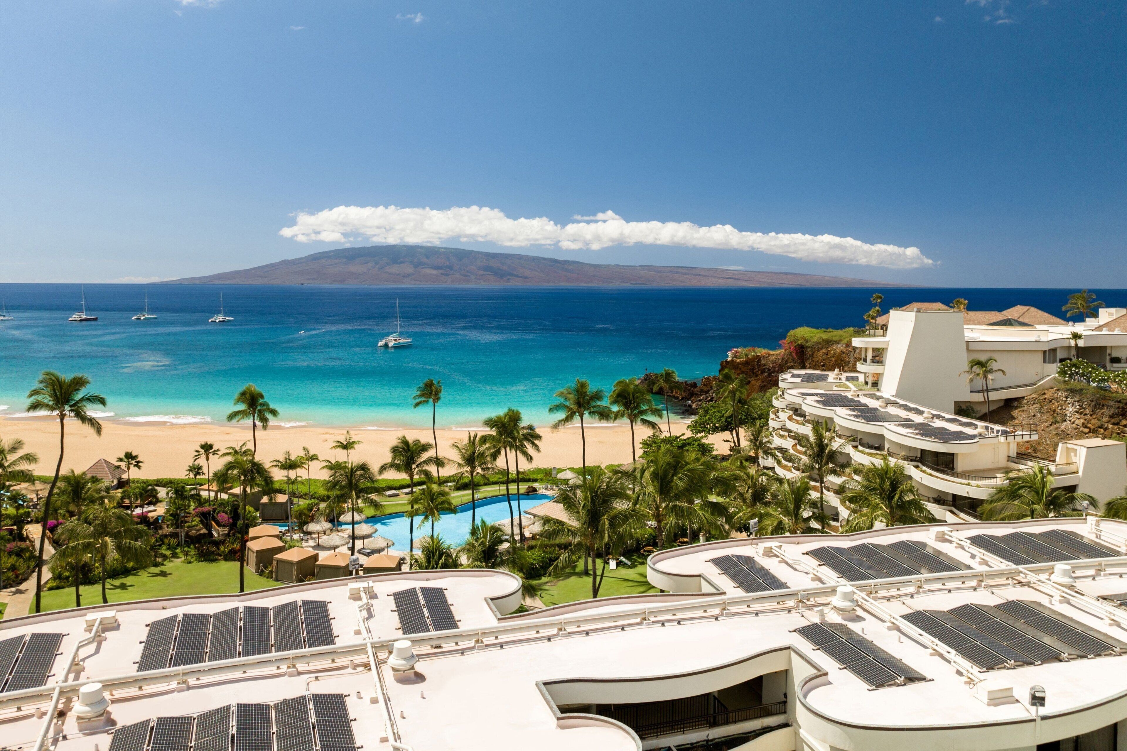 A resort with a pool, solar panels, and a beach view.