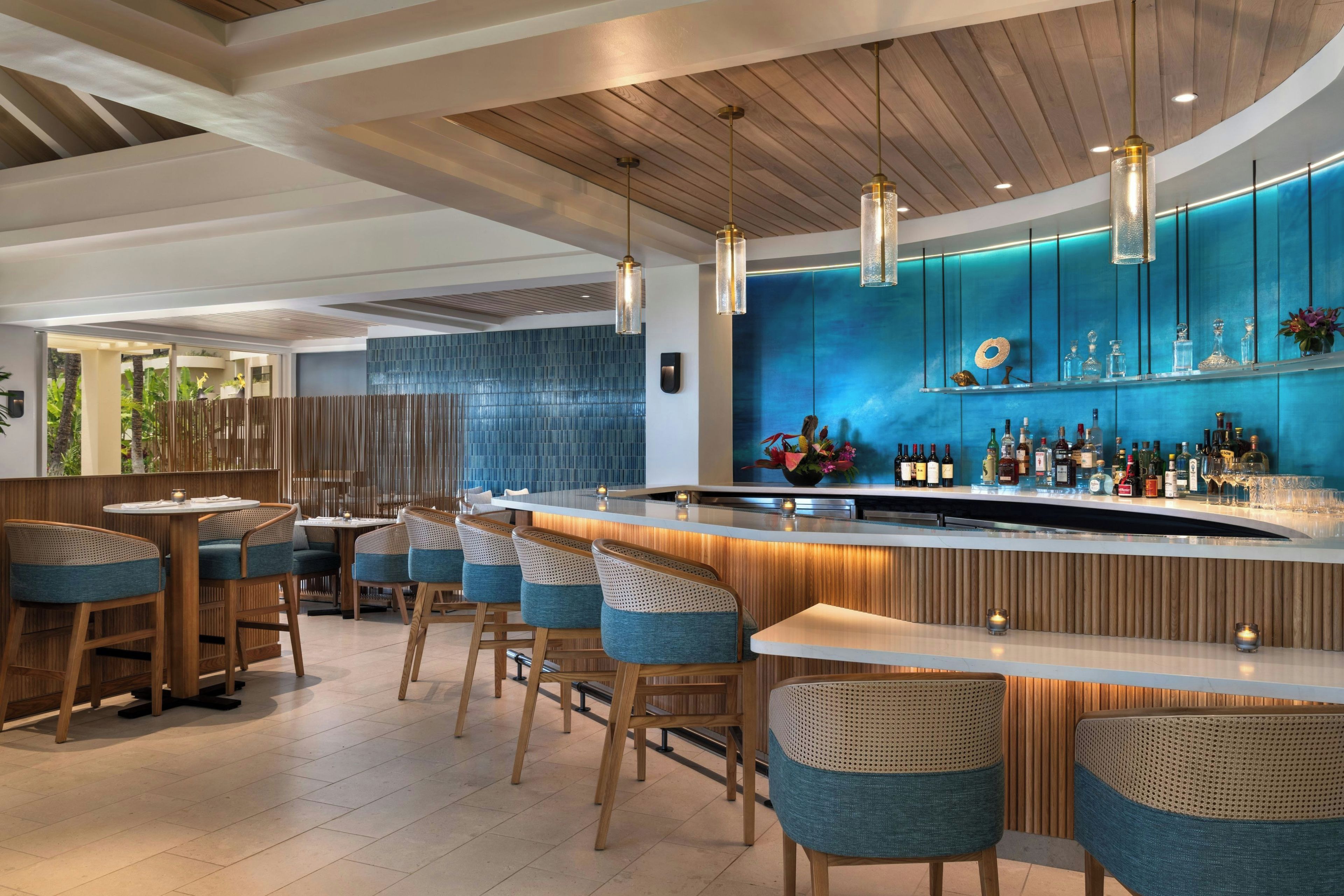 A modern bar area with wooden ceiling beams, a blue accent wall, and a bar counter with stools.