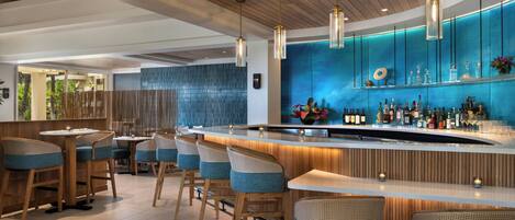 A modern bar area with wooden ceiling beams, a blue accent wall, and a bar counter with stools.