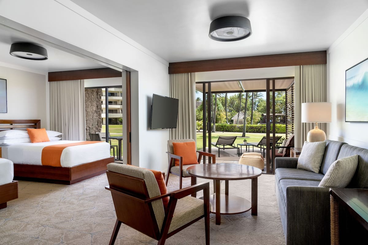 A hotel room with a bed, a sofa, a TV, and a view of the outdoors.